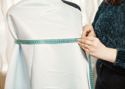 women measuring dummy with white top using centimetre tape